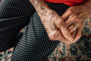 An elderly woman in her 80's with hands clasped together